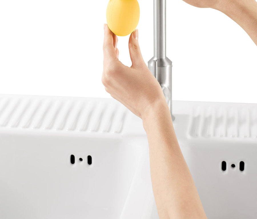 Une femme fixe l'embout détartrant pour robinet, jaune.