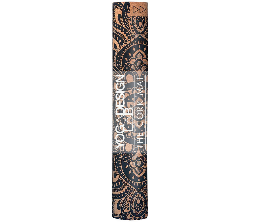 Un tapis de yoga en liège enroulé avec un motif ornemental noir.