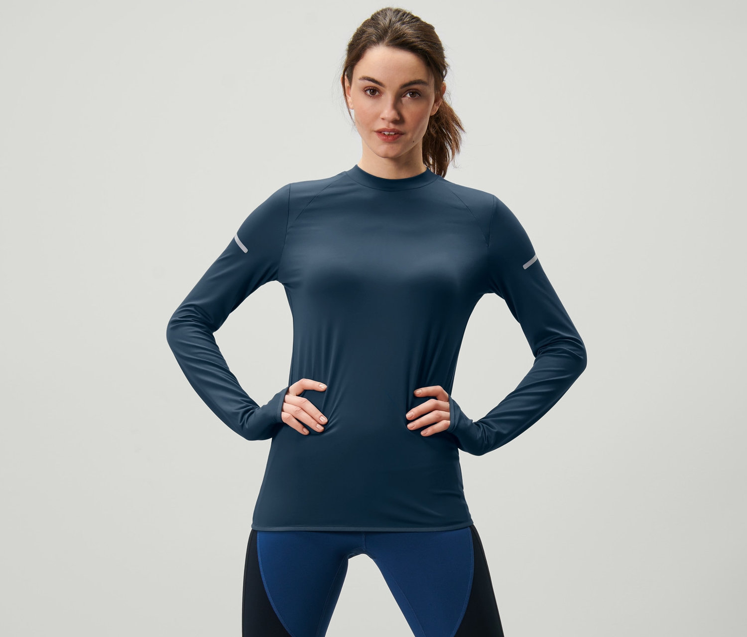 Femme posant en t-shirt fonctionnel manches longues bleu foncé.