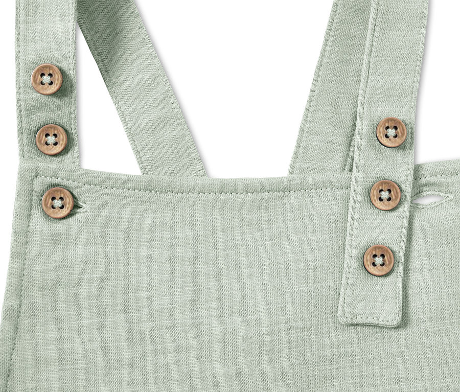 Détail d'une salopette pour bébé de couleur menthe avec des boutons en bois.