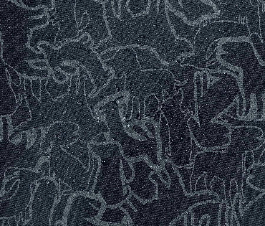 Gros plan sur une veste de pluie thermique pour enfant avec des éléments réfléchissants et un motif animalier, sur laquelle se trouvent des gouttes d'eau.