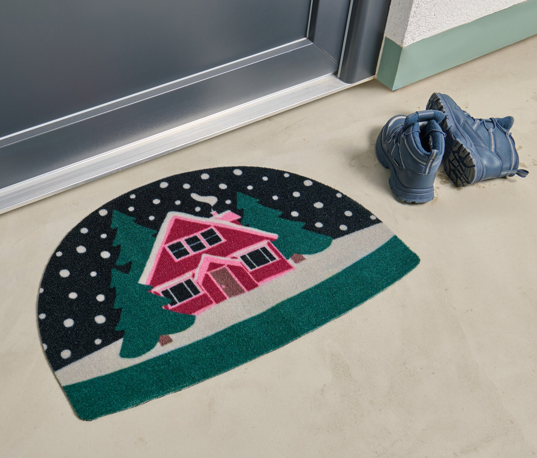 Un paillasson avec un motif de paysage enneigé se trouve devant une porte.