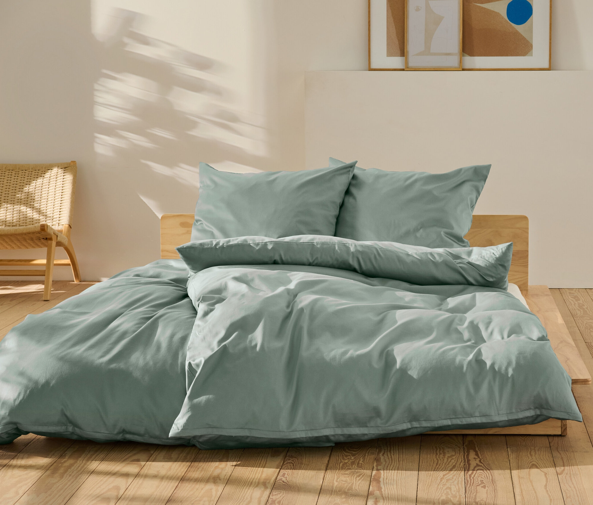 Parure de lit en satin de coton vert de taille standard et grande taille sur un lit.