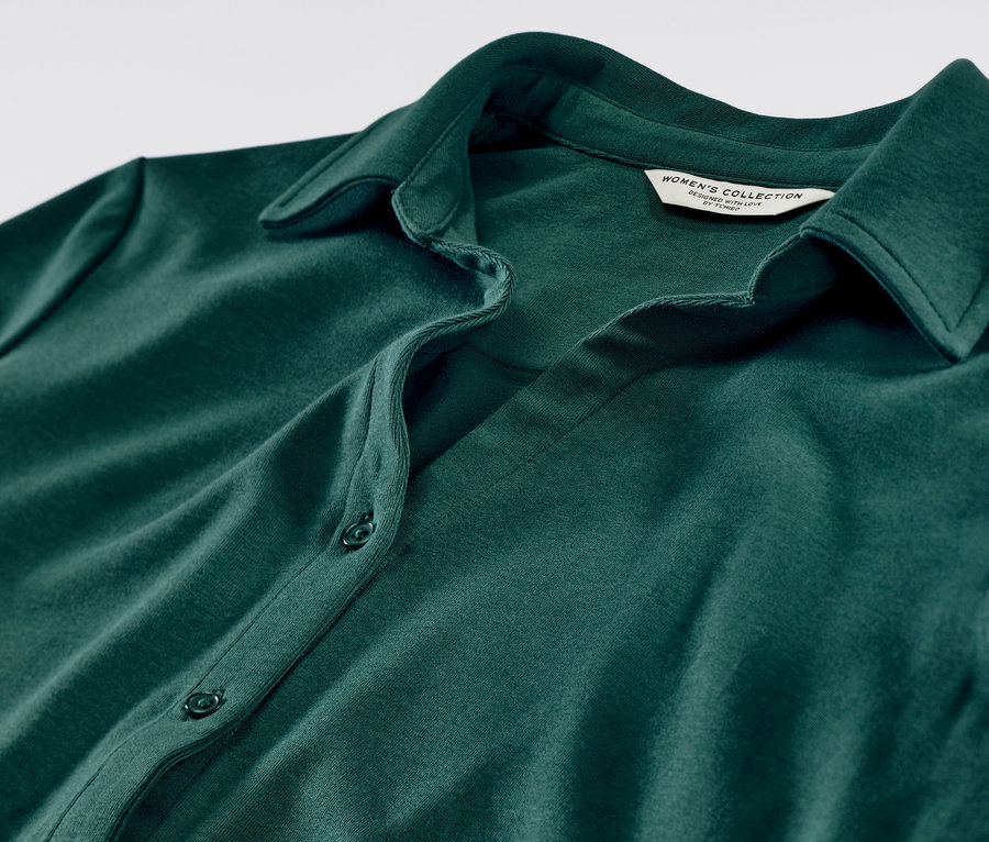 Gros plan sur une blouse verte avec patte de boutonnage.