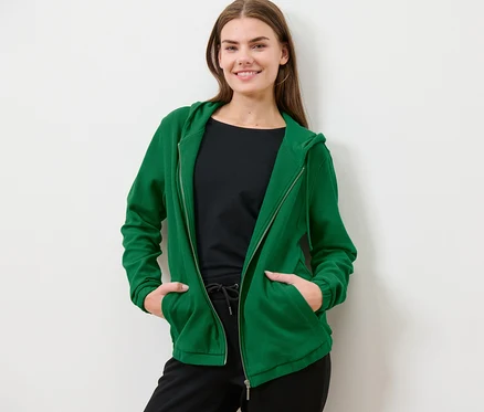 Femme posant en jaquette de sweat verte.