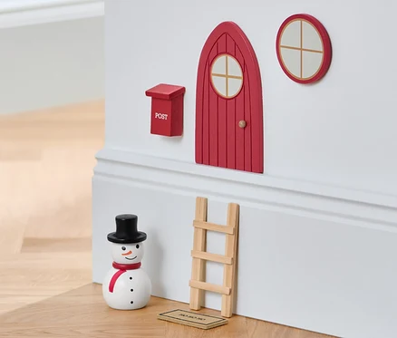 Un set porte de lutin sur un mur avec un bonhomme de neige et un tabouret.