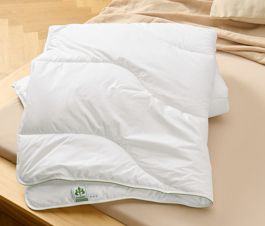 Une couette blanche pliée irisette® greenline « Aerelle® Blue » est posée sur un lit.