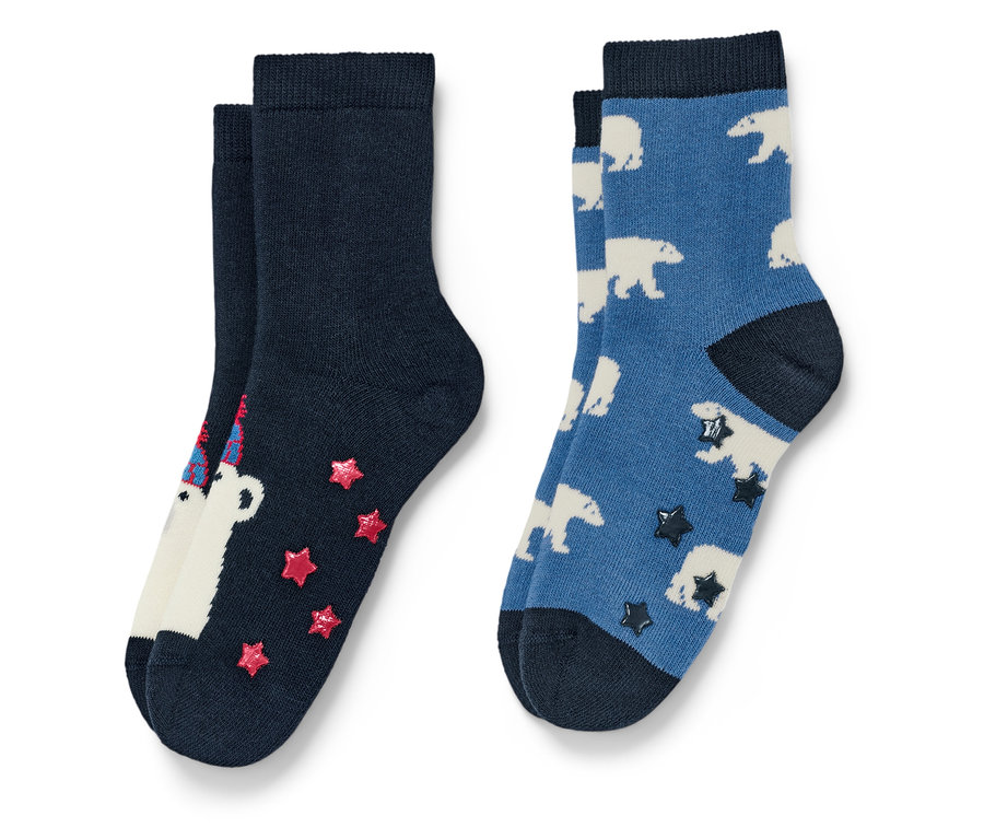 Deux paires de chaussettes. Une paire bleu marine avec un ours blanc portant un chapeau d'anniversaire et des étoiles rouges, l'autre paire bleue avec des ours polaires blancs et des étoiles foncées.
