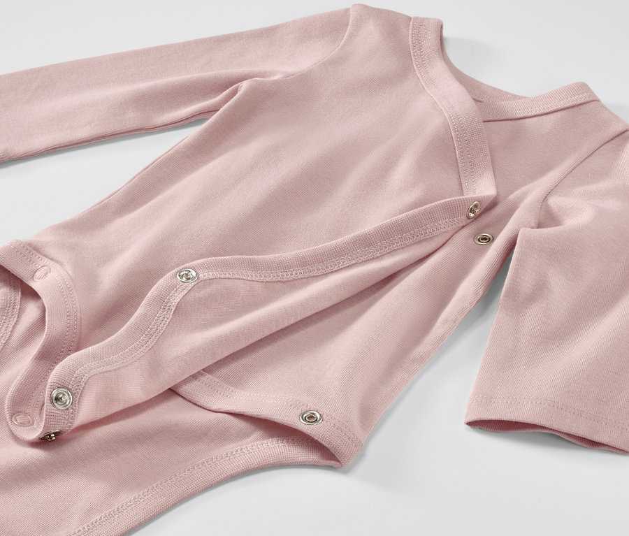 Gros plan sur un body rose évolutif pour bébé à manches longues, fermé par des boutons-pression.