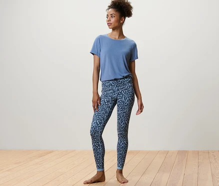 Une femme debout porte un legging de sport réversible bleu/bleu clair et un t-shirt bleu.