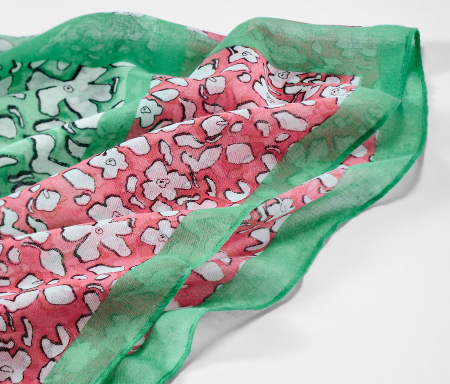Vue détaillée d'un foulard loop imprimé avec un motif floral vert et rose.