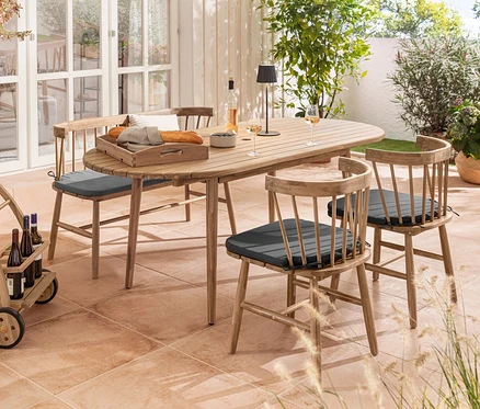 Extérieur avec table ovale extensible, chaises de salle à manger avec coussin d’assise, banc avec assise rembourrée et lampe de table d’extérieur à LED rechargeable noire.