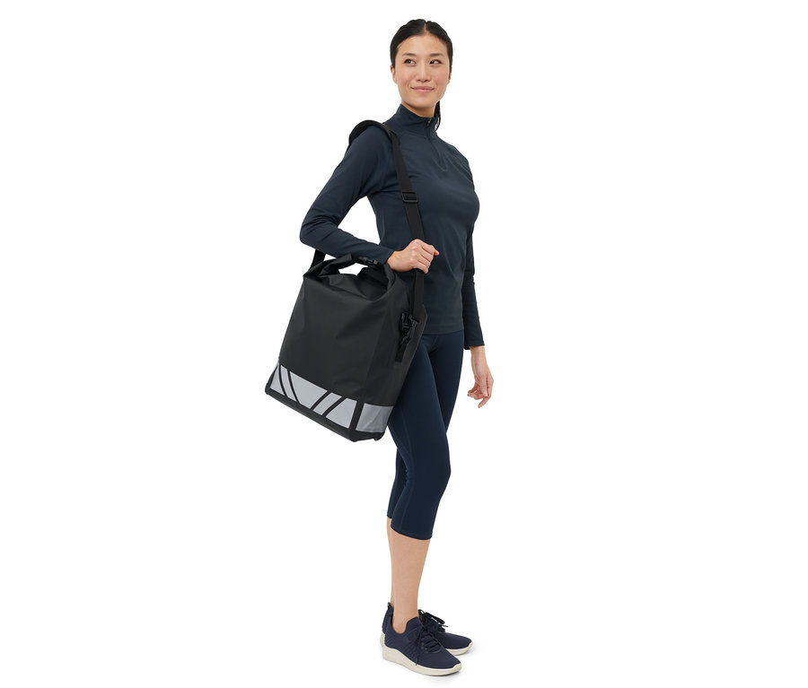 Femme portant une sacoche imperméable à bandoulière pour vélo sur l'épaule.