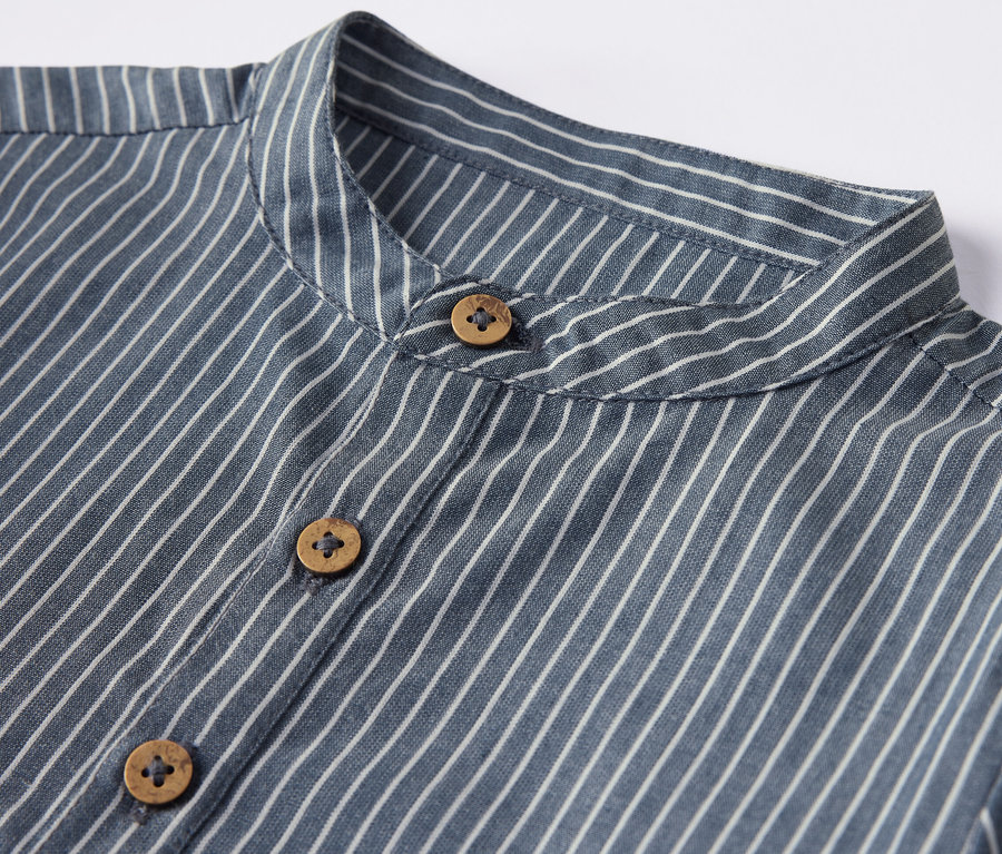 Gros plan sur une chemise pour enfant rayée avec des boutons en bois.