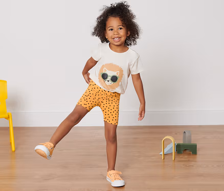 Une fille se tient sur une jambe et porte 2 leggings cyclistes pour enfant.