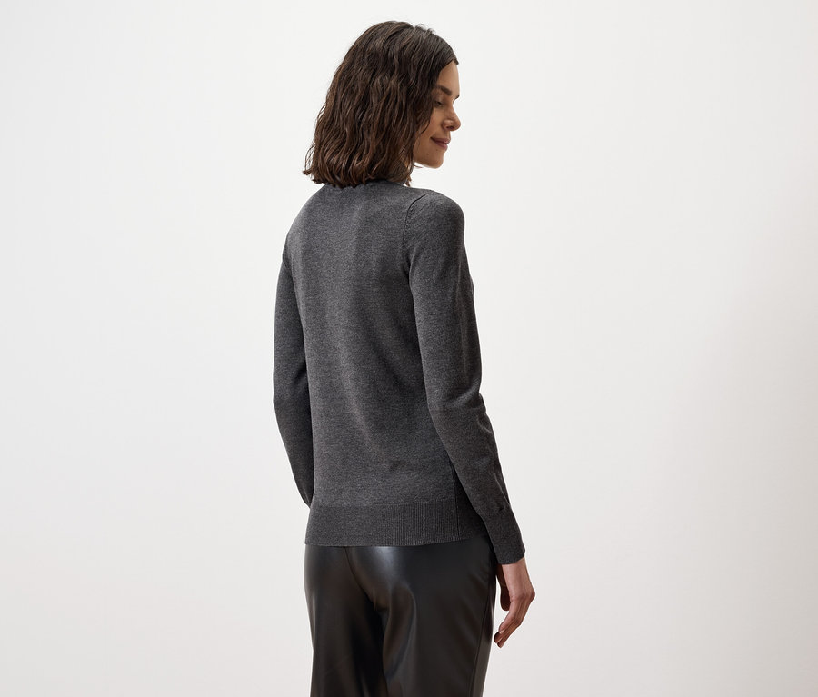 Vue arrière d'une femme aux cheveux bruns ondulés portant un pull gris et un pantalon en cuir noir.