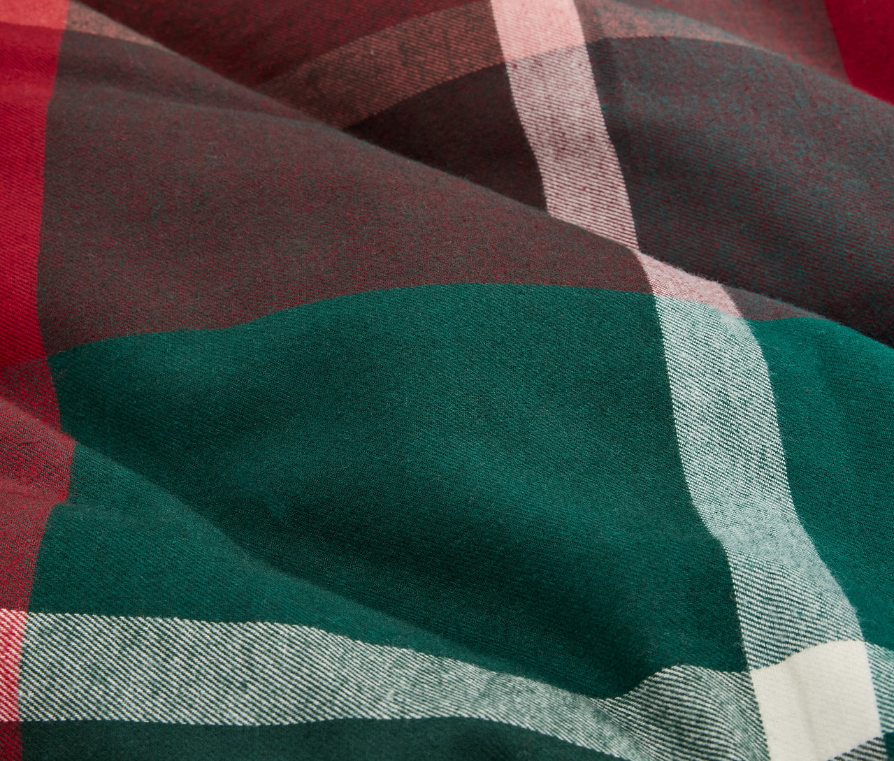Gros plan sur un tissu à carreaux dans les tons vert, marron, rouge et blanc.