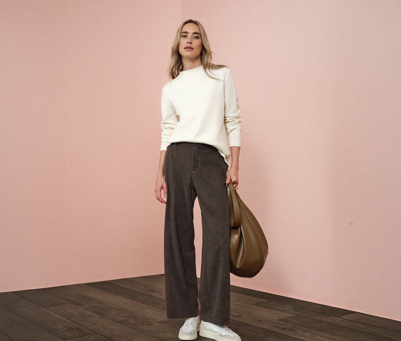 Femme debout tenant un sac, elle porte un pantalon Straight Leg Street One, un pull blanc et des baskets.