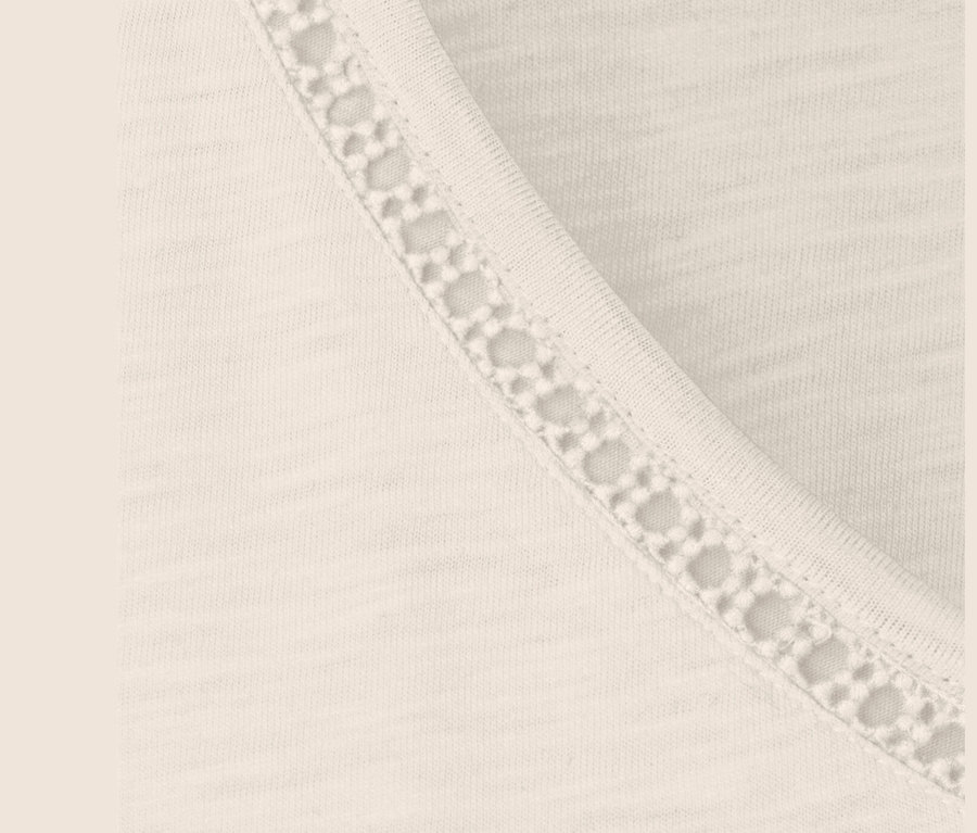 Gros plan sur un t-shirt en mélange modal blanc crème avec bordure en dentelle.