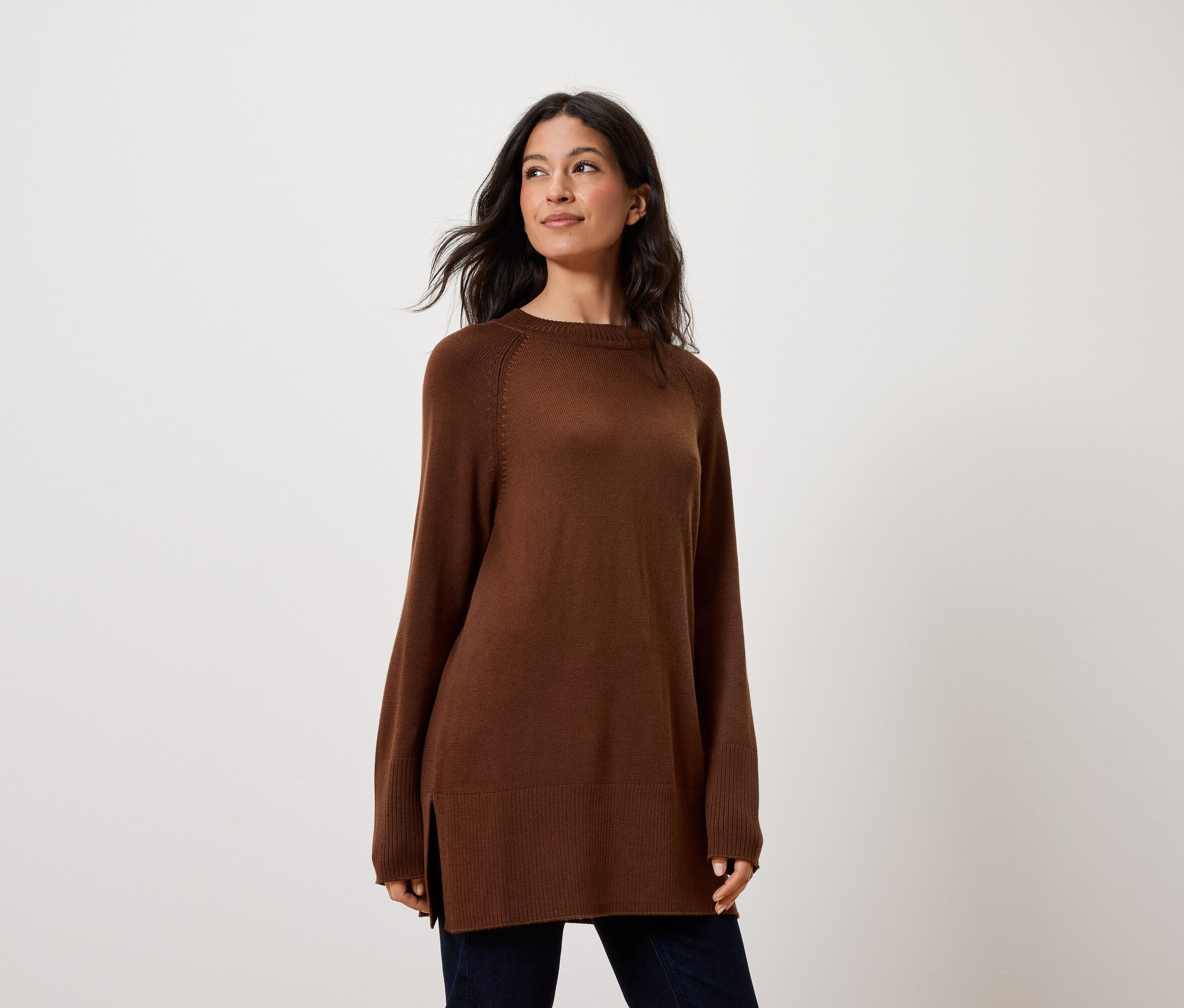 Femme portant un pull marron à manches longues avec fentes latérales.