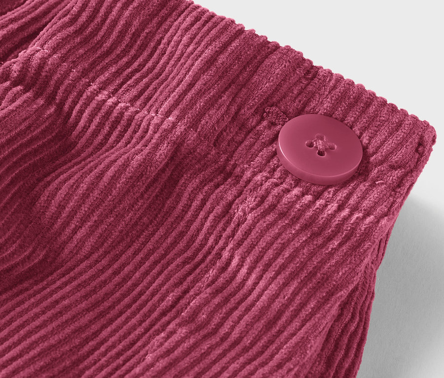 Gros plan d'un tissu de velours côtelé bordeaux avec un bouton.