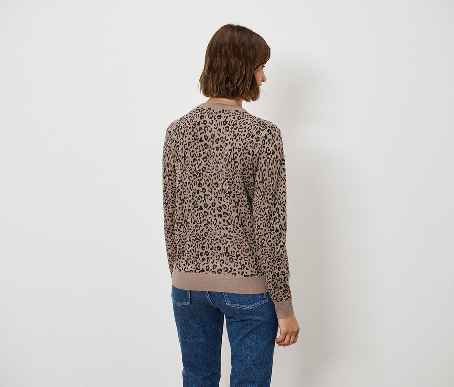 Vue arrière d'une femme aux cheveux bruns courts portant un chemisier marron à motif animalier et un jean bleu.