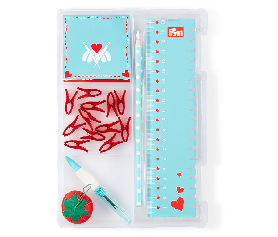 Vue de dessus d'un kit de démarrage de couture Prym "Love" dans un emballage en plastique transparent. Il contient des épingles, des pinces, une aiguille et une règle.