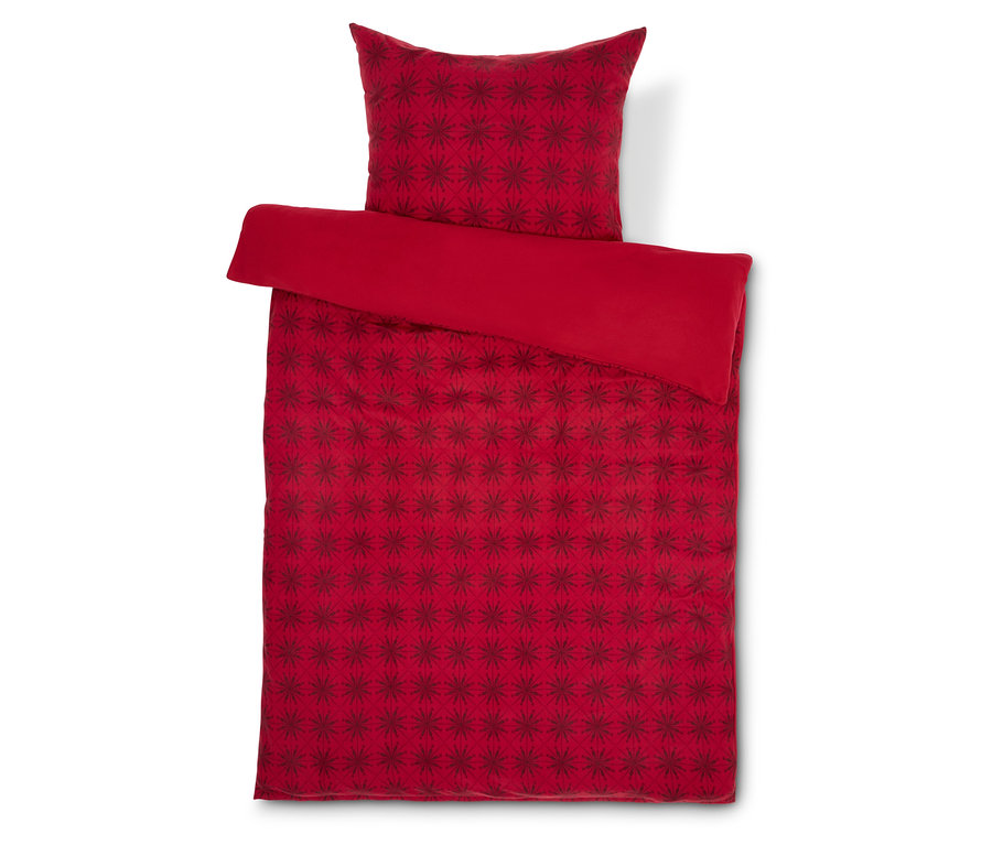 Linge de lit rouge avec motif étoile et oreiller rouge sur fond blanc.