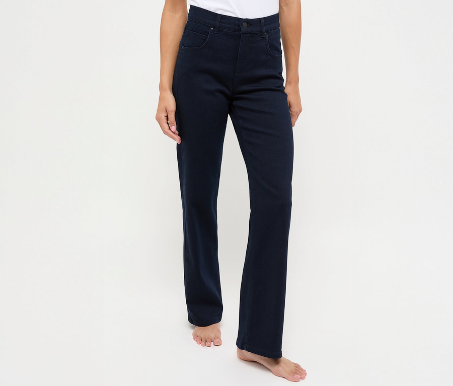 Une femme se tenant devant un fond blanc porte un jean bleu foncé Angels Denim « Lara », coupe droite.