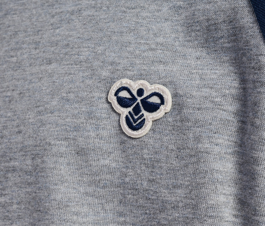 T-shirt gris avec manches raglan bleues et logo Hummel.