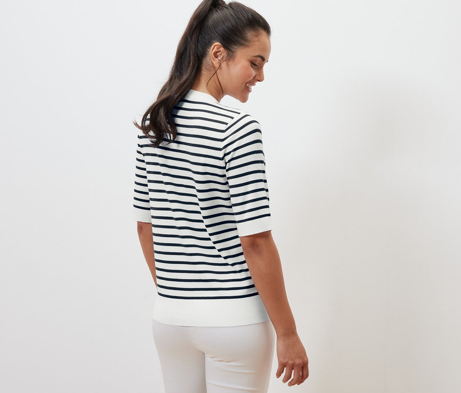 Une femme, vue de dos, porte un pull en tricot fin à rayures bleu marine.