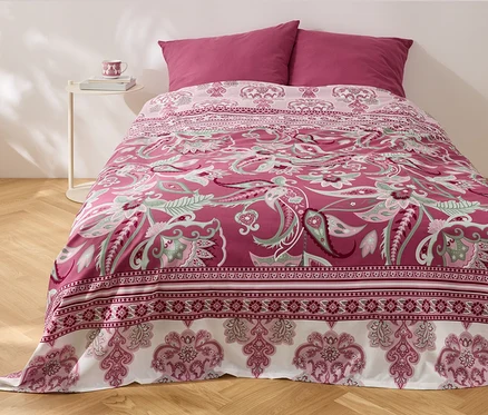 Un lit avec un dessus-de-lit multifonction en renforcé à motif floral et deux oreillers.