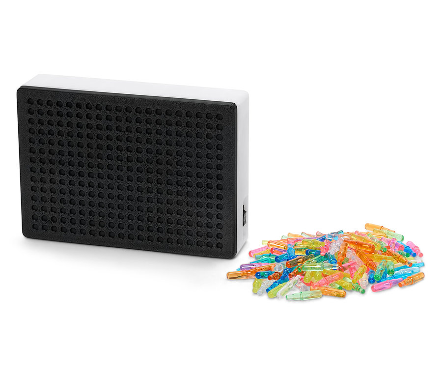 Table lumineuse noire avec cadre blanc à côté d'un tas de chevilles colorées.