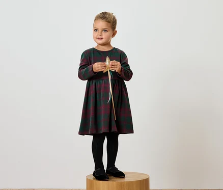 Une fille en robe à carreaux tient une étoile dorée.