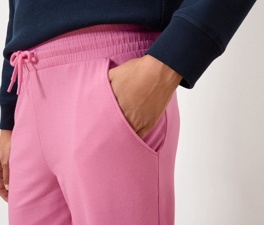Gros plan d'une femme portant un pantalon de jogging rose avec une main dans la poche.