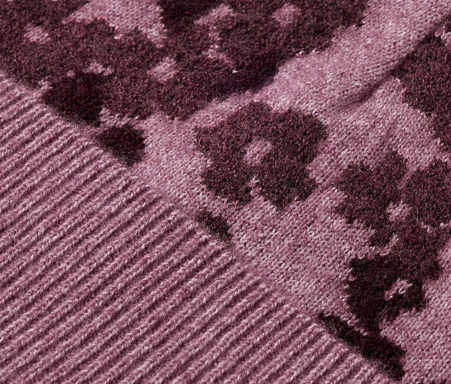 Gros plan d'un pull tricoté violet à motif floral.
