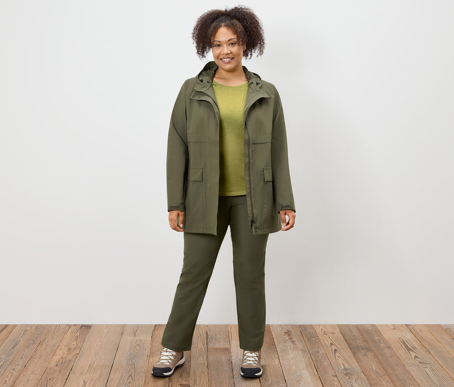 Femme debout portant un manteau, un pantalon et des chaussures vert olive.