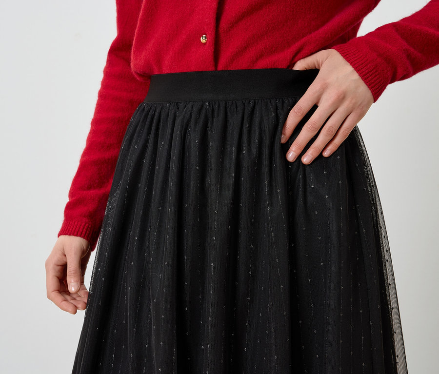 Vue partielle d'une femme portant un cardigan rouge et une jupe noire.