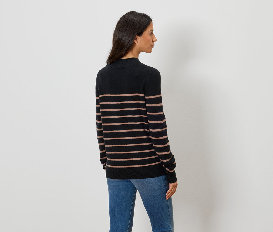 Vue arrière d'une femme aux cheveux bruns foncés mi-longs portant un pull à col roulé noir à rayures horizontales marron et un jean bleu.