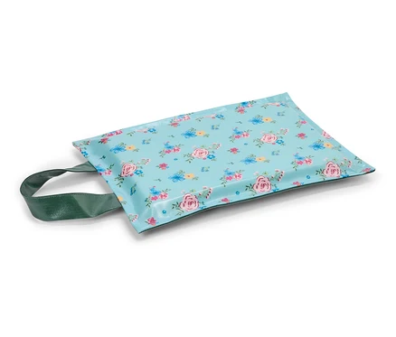 Un coussin pour genoux à fleurs bleues avec une poignée verte sur fond blanc.