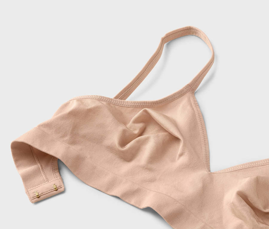 Gros plan d'un soutien-gorge couleur chair à bretelles fines avec des crochets dorés.