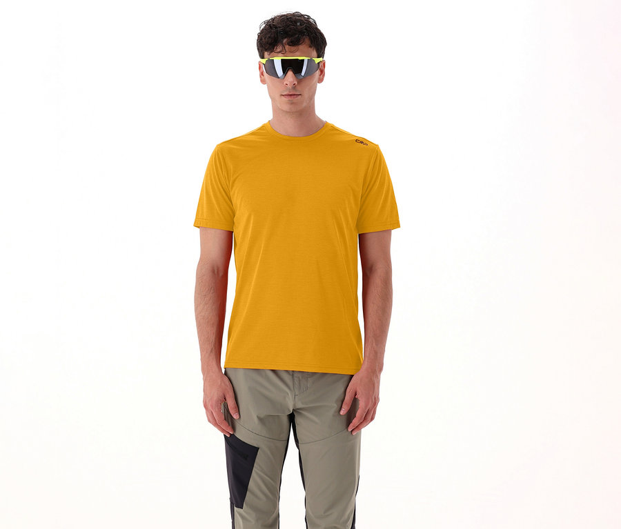 Un homme portant des lunettes de soleil jaunes et un t-shirt pour homme CMP en maille piquée, curcuma, se tient devant un fond blanc.