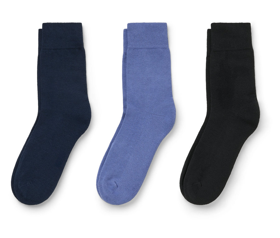 Trois chaussettes bleu marine, violet et noir sont posées sur un fond blanc.