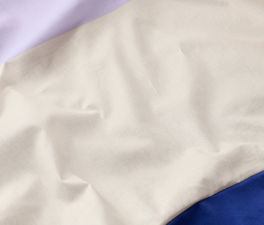 Gros plan d'un tissu drapé en lilas, crème et bleu.