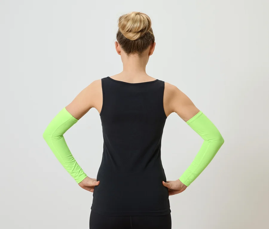 Vue arrière d'une femme portant un chignon, un débardeur noir et des manchettes vert néon, les mains sur les hanches.