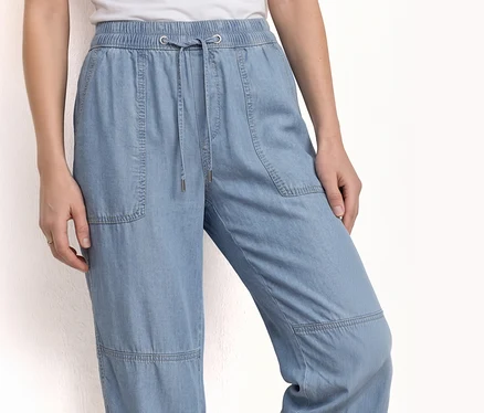 Une personne porte un jogging Street One »Bonny« en denim bleu clair avec cordon de serrage et poches.