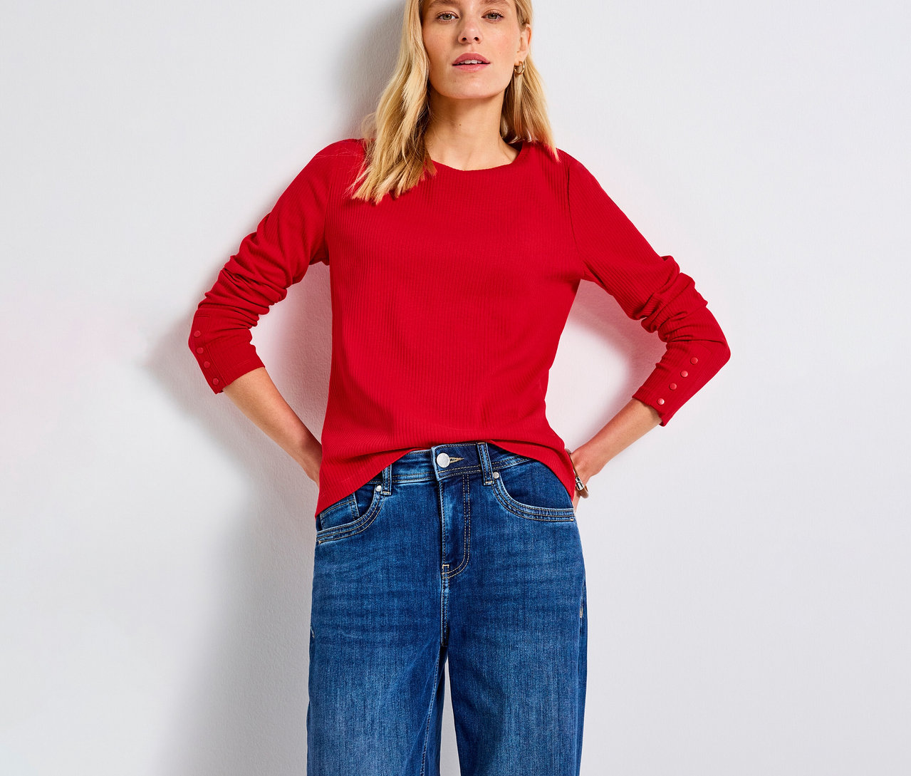 Femme portant un maillot côtelé Street One rouge et un jean.