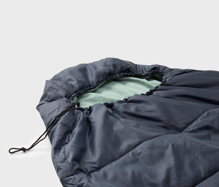 Gros plan d'un sac de couchage bleu foncé avec une doublure vert clair et un cordon de serrage noir.