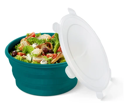 Salade dans un bol turquoise avec un couvercle blanc détaché.