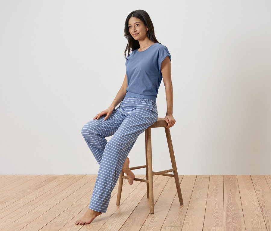 Femme assise sur un tabouret portant un pyjama bleu rayé.